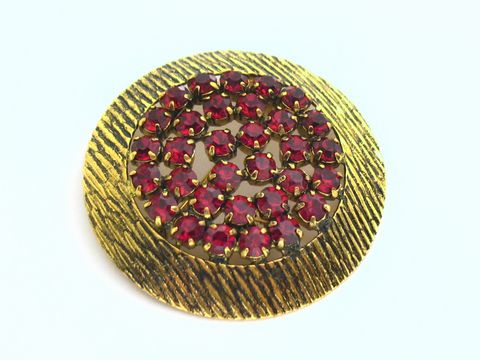 Runde Strass Brosche mit roten gefassten Strass Steinen, hergestellt von Juwelier Harnisch. Die Brosche weist ein harmonisches Design und strahlende Farben auf. Ideal für elegante Outfits.