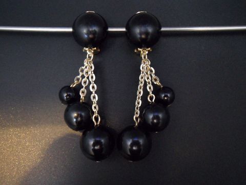 Schwarze Ohrclips mit goldfarbenen Kettenelementen und verschiedenen schwarzen Kugeln aus Kunstharz, zeitloses Design, Hersteller Juwelier Harnisch.