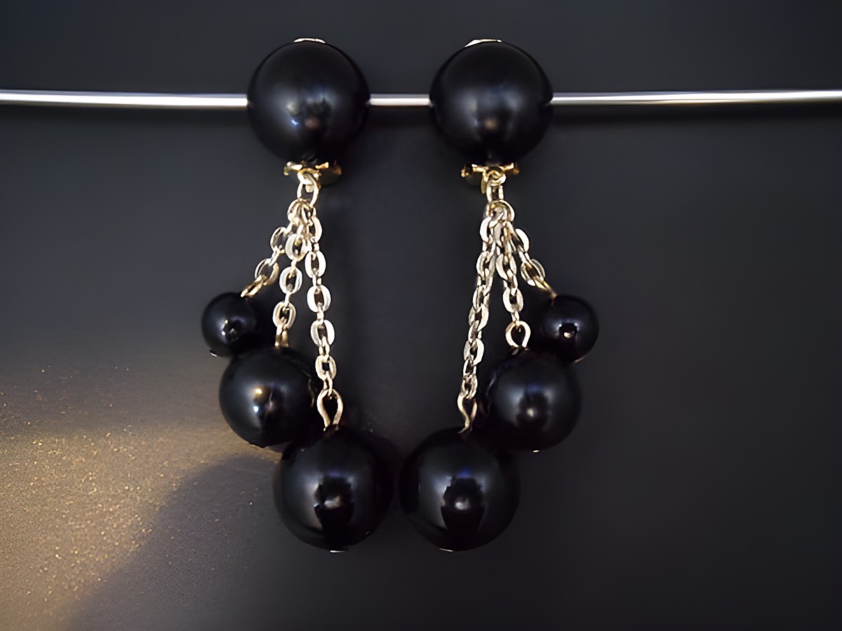 Schwarze Ohrclips mit goldfarbenen Kettenelementen und verschiedenen schwarzen Kugeln aus Kunstharz, zeitloses Design, Hersteller Juwelier Harnisch.