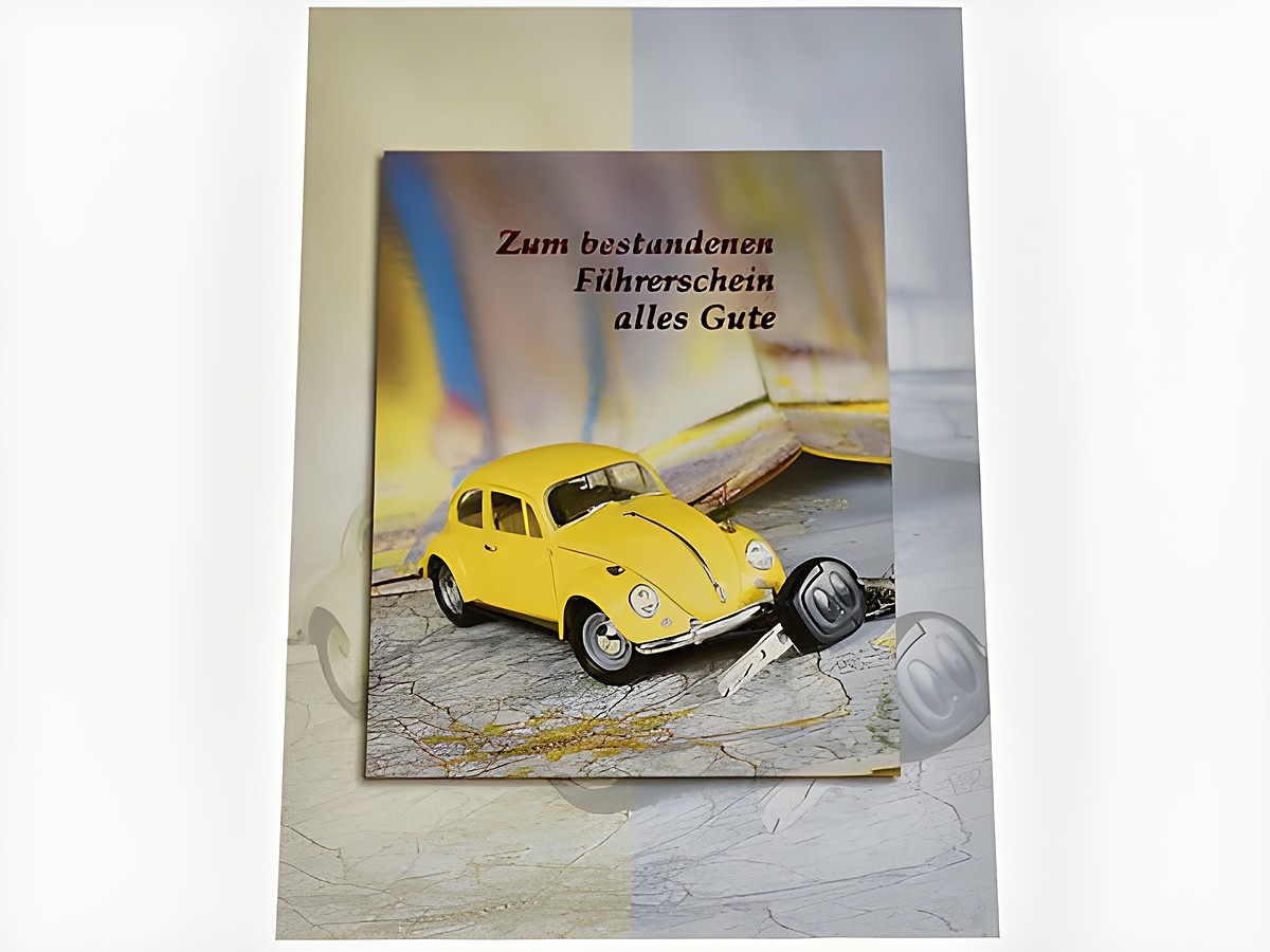 Gelbes Modellauto neben Autoschlüssel und Landkarte auf Glückwunschkarte zum bestandenen Führerschein, Hersteller Juwelier Harnisch.