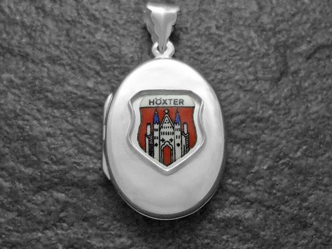 Ein silbernes Medaillon mit dem Wappen der Stadt Höxter, das ein rot-weißes Schild mit einem historischen Gebäude zeigt. Hersteller ist Juwelier Harnisch aus Nordrhein-Westfalen.