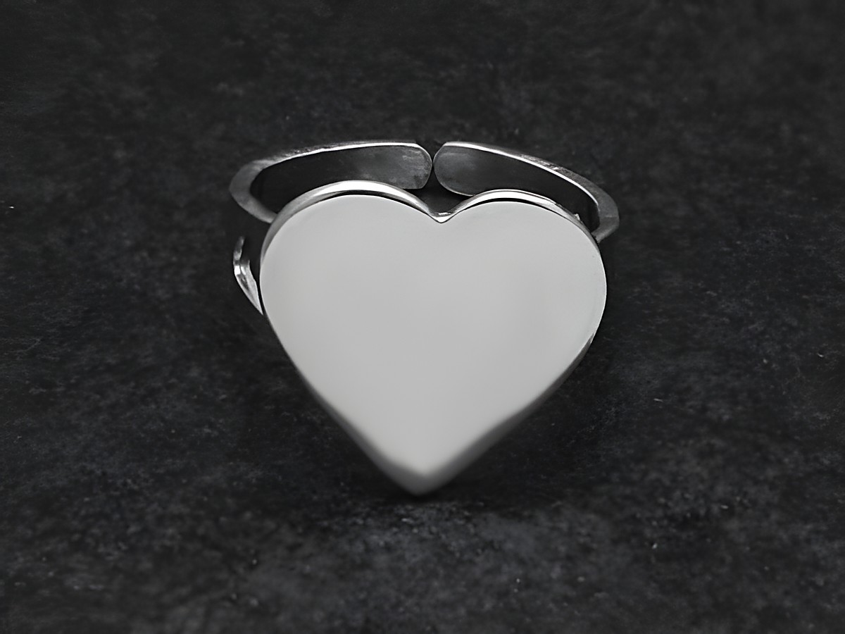 Silberring in Herzform, glatt, in wenig verstellbarer Größe, Hersteller: Juwelier Harnisch, ohne Stein, auf schwarzem Hintergrund abgebildet.