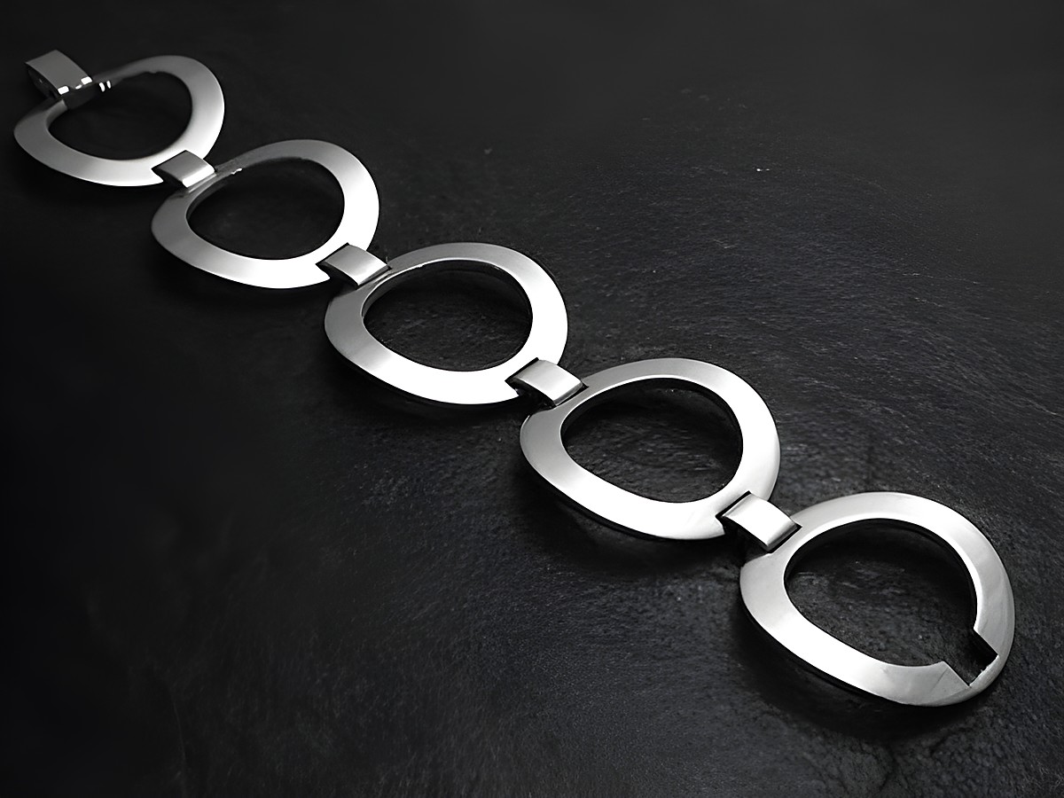 Silberarmband futuristisch 18 cm Design von Juwelier Harnisch ohne Stein, besteht aus mehreren eleganten und geschwungenen Elementen, präsentiert auf einem dunklen Untergrund.