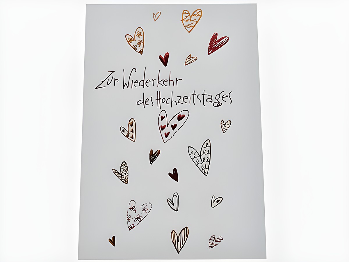 Weiße Hochzeitskarte mit roten Herzchen, verziert mit verschiedenen Herzmotiven und dem Text zur Wiederkehr des Hochzeitstages, Hersteller Juwelier Harnisch.