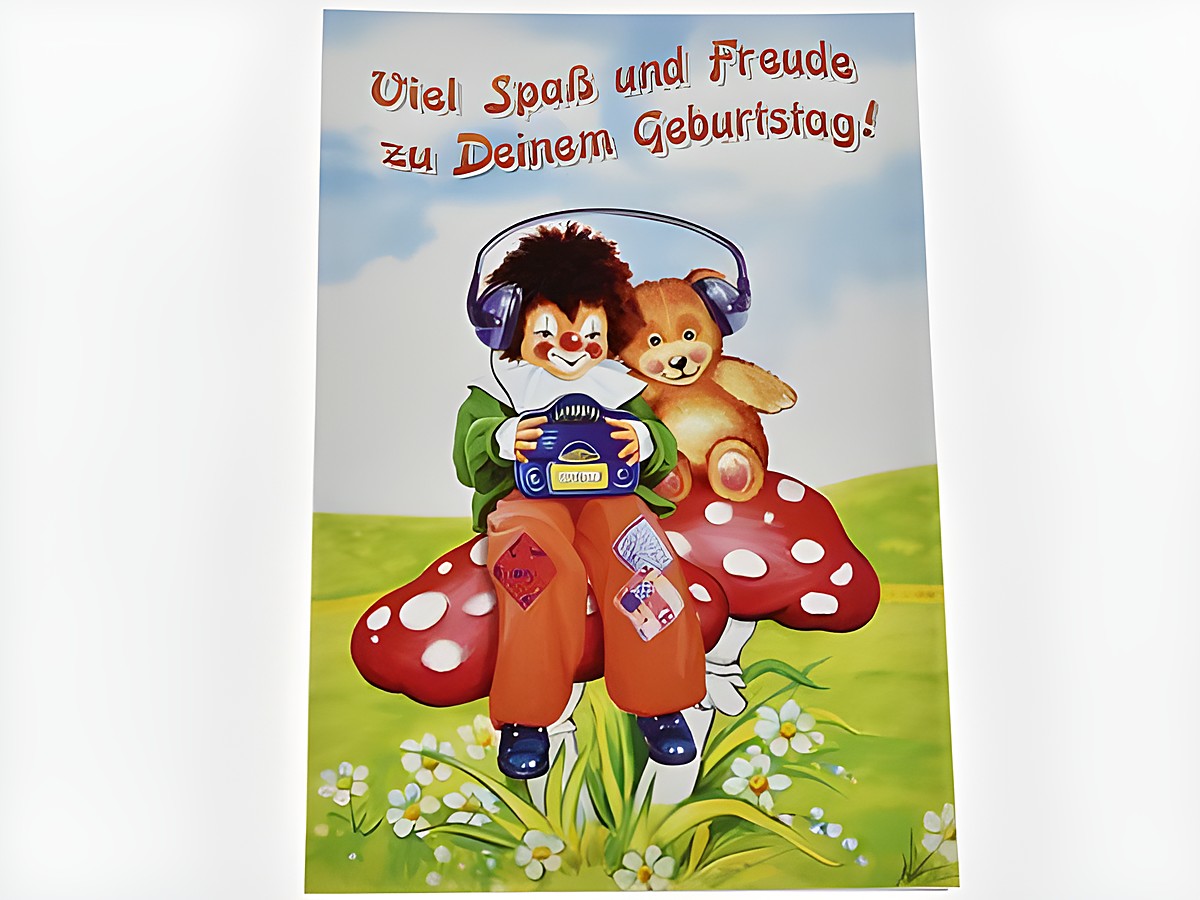 Eine Geburtstagskarte mit einem Clown, der einen Teddy umarmt, sitzt auf einem roten Glückspilz. Im Hintergrund stehen Blumen und der Text Viel Spaß und Freude zu Deinem Geburtstag.