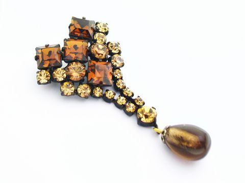Gelb-Braune Strass Damen Brosche mit sexy Look, hergestellt von Juwelier Harnisch. Die Brosche ist reich verziert mit Strasssteinen in Gelb und Braun und hat einen eleganten Tropfenanhänger.