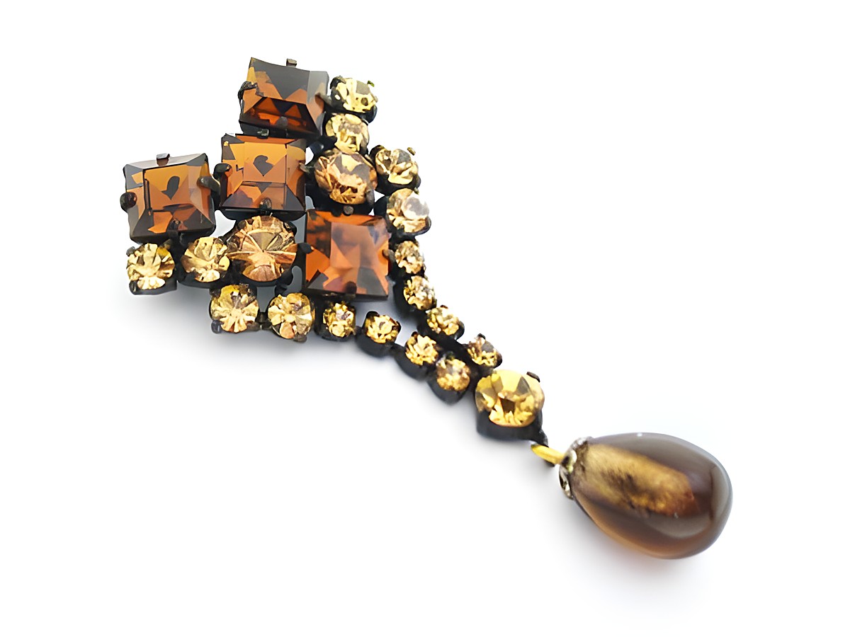 Gelb-Braune Strass Damen Brosche mit sexy Look, hergestellt von Juwelier Harnisch. Die Brosche ist reich verziert mit Strasssteinen in Gelb und Braun und hat einen eleganten Tropfenanhänger.