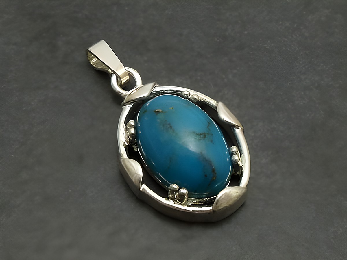 Designer Silber Anhänger in ovaler Form mit einem türkisfarbenen Stein, umgeben von einem filigranen Silberrand, Hersteller Juwelier Harnisch, ergänzt durch weitere Steine.