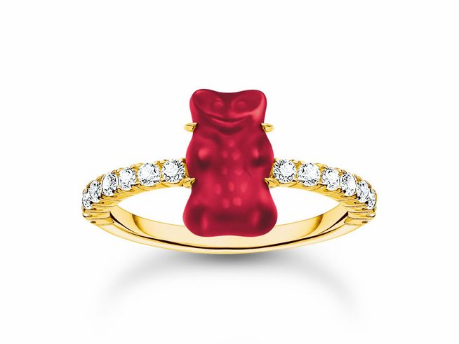 Ein goldfarbener Ring mit einem roten Gummibärchen und Zirkonia-Steinen an der Fassung, gefertigt von Thomas Sabo, Modell TR2459-414-10-50 HARIBO, Größe 50.