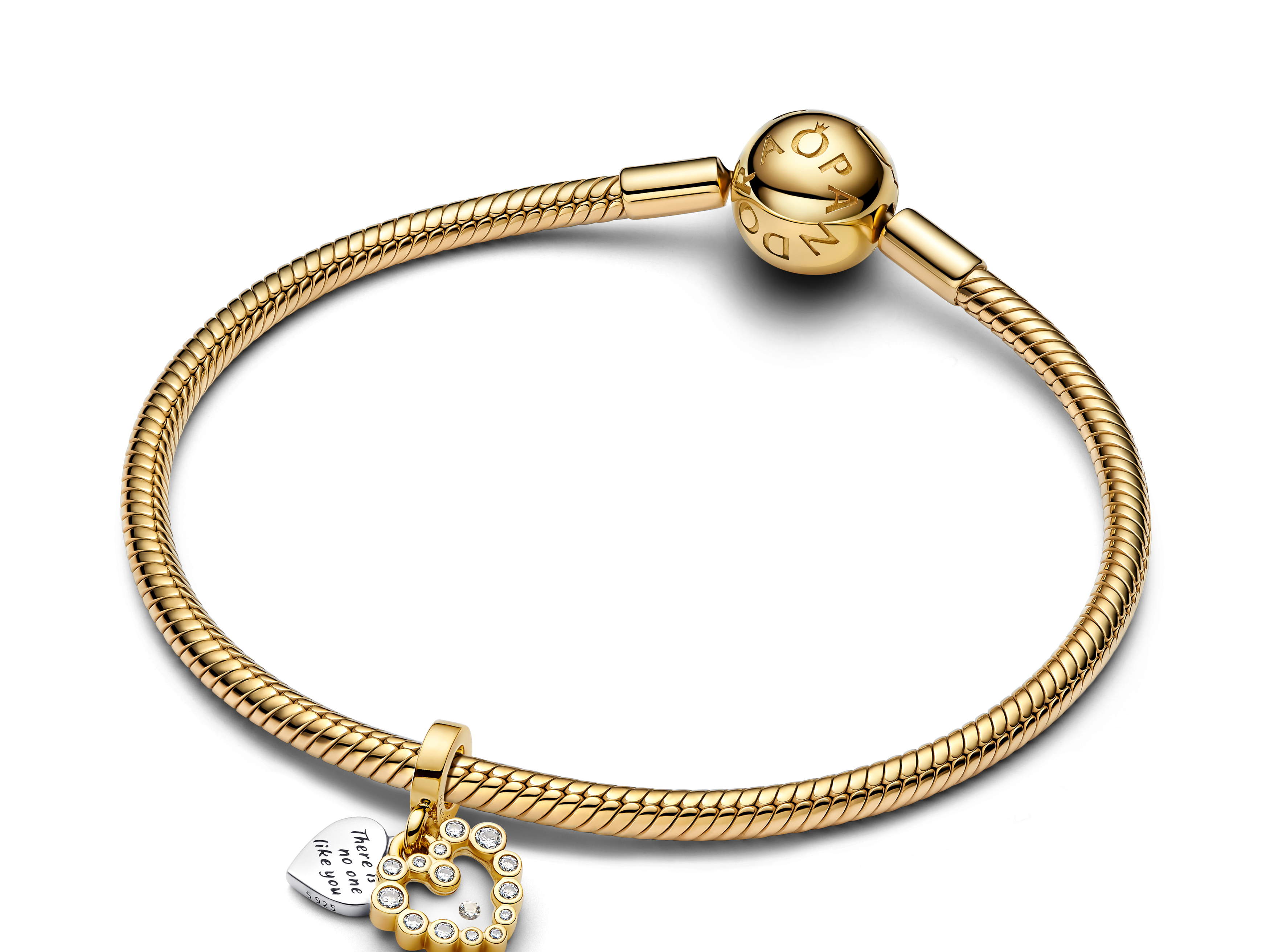 Der Pandora Charm zeigt einen herzförmigen Anhänger aus Sterling Silber mit Gelbgold Vergoldung und Emaille, verziert mit Zirkonia-Steinen, an einem goldenen Armband.