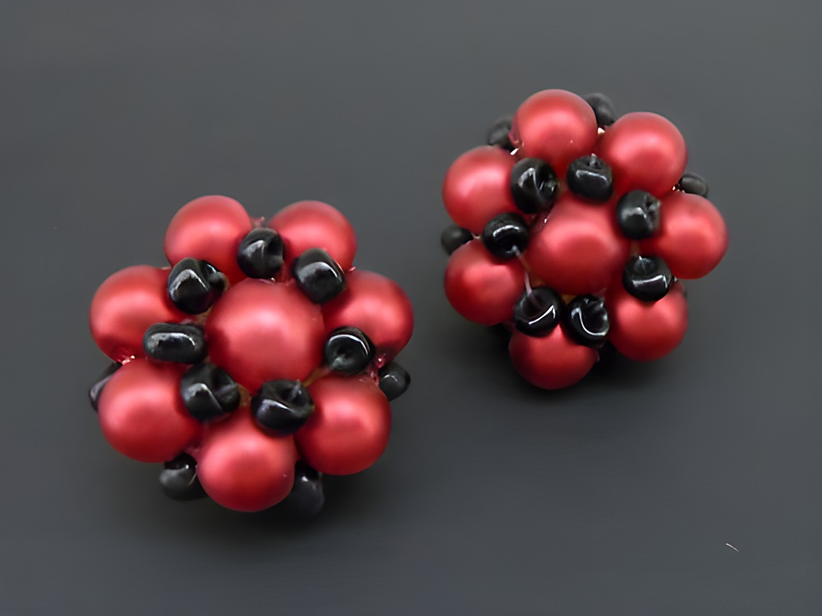 Ohrclip in rot-schwarz mit blumigem Design, verziert mit goldfarbenen synthetischen Zuchtperlen, hergestellt von Juwelier Harnisch. Ideal für jeden Anlass.