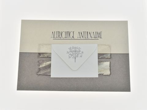 Trauerkarte in grau mit der Aufschrift "Aufrichtige Anteilnahme" und einem gefalteten Umschlag, der mit einem dezenten Baum-Motiv verziert ist, vom Hersteller Juwelier Harnisch.