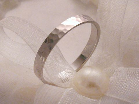 Trauring Ehering aus Weißgold 333 in Größe 64/20,4 mit einer gehämmerten Oberfläche, elegant präsentiert auf einem dekorativen weißen Stoff mit Perle. Hersteller: Juwelier Harnisch.