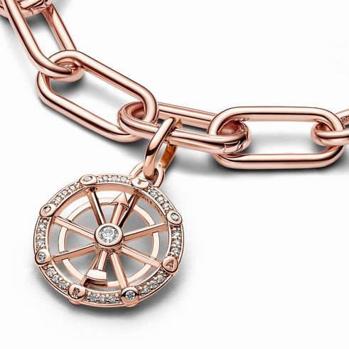 Ein roségold vergoldeter Charm von Pandora ME in Form eines Glücksrades mit klaren Zirkonia, der an einer Kette hängt und einen eleganten, modernen Look bietet.