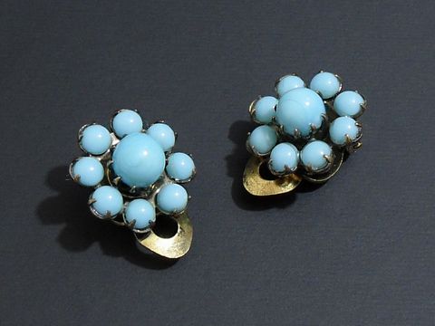 Strass Ohrclip grazil in türkis und goldfarben, hergestellt von Juwelier Harnisch, mit eleganter Blumengestaltung und funkelnden Steinen für einen stilvollen Auftritt.