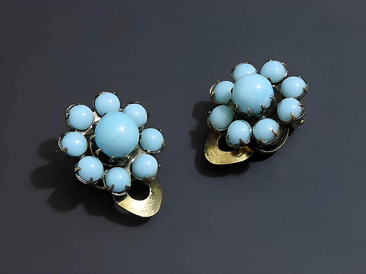 Strass Ohrclip grazil in türkis und goldfarben, hergestellt von Juwelier Harnisch, mit eleganter Blumengestaltung und funkelnden Steinen für einen stilvollen Auftritt.