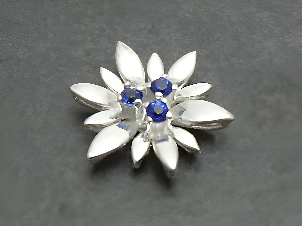 Silber Anhänger -City- 17x17mm mit einer Blüte aus synthetischem Spinell in der Mitte, umgeben von blattförmigen Elementen, hergestellt von Juwelier Harnisch, stilvoll und elegant.