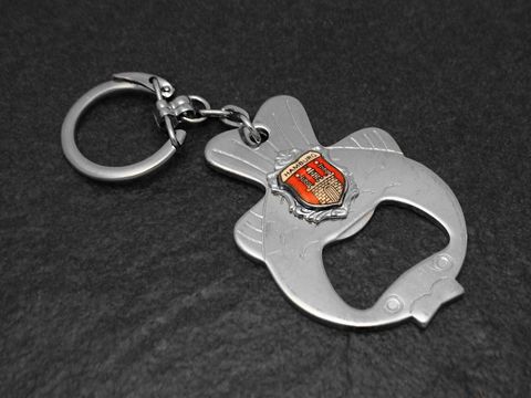 Schlüsselanhänger und Flaschenöffner in Fischform mit rotem Wappen, Hersteller Juwelier Harnisch, silberfarben, ideal für den praktischen Gebrauch und als Geschenk.