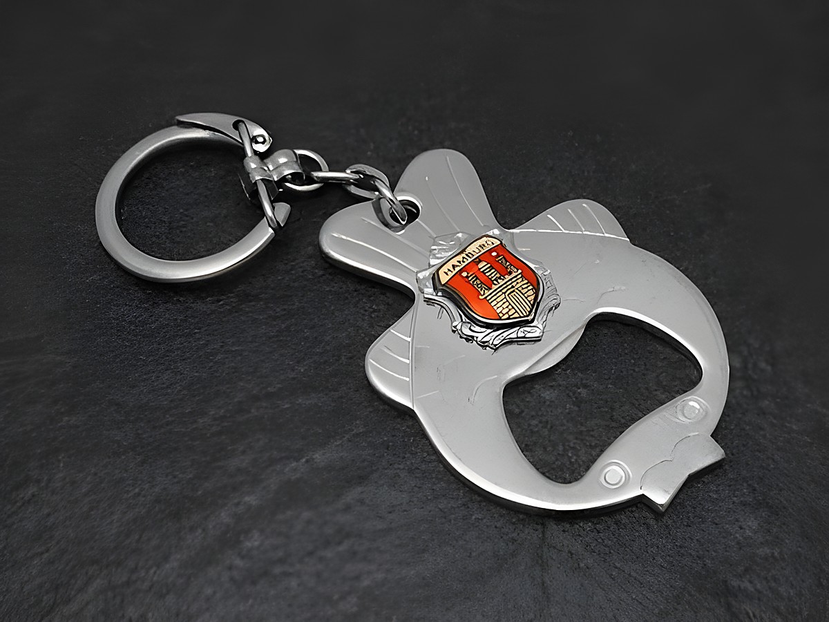 Schlüsselanhänger und Flaschenöffner in Fischform mit rotem Wappen, Hersteller Juwelier Harnisch, silberfarben, ideal für den praktischen Gebrauch und als Geschenk.