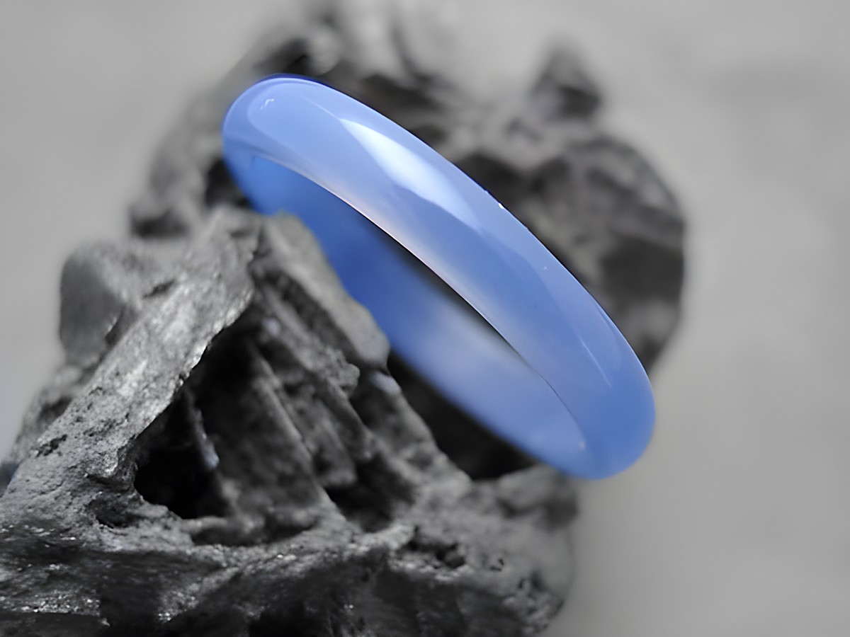 Steinring schlicht echter Achat blau 2,8 x 1,9 mm Gr. 60,5 Hersteller Juwelier Harnisch bis Gr. 60. Der Ring präsentiert sich in einem sanften Blauton und ist auf einem dunklen Untergrund abgebildet.