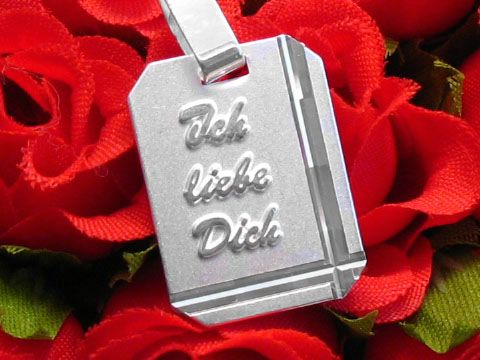 Diamantschliff Silber Gravurplatte rechteckig mit eingraviertem Text "Ich liebe Dich", auf rotem Rosenhintergrund präsentiert, Hersteller Juwelier Harnisch.