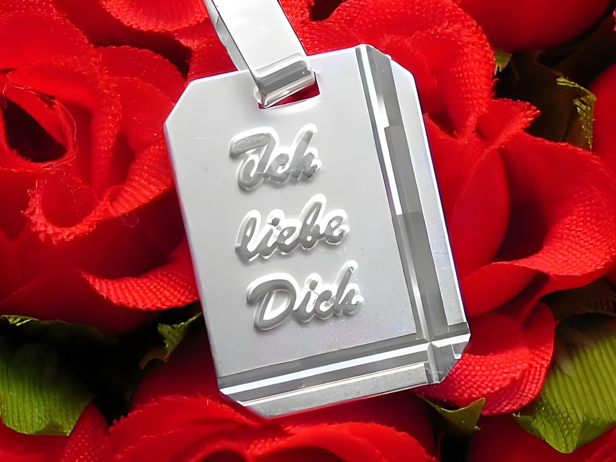 Diamantschliff Silber Gravurplatte rechteckig mit eingraviertem Text "Ich liebe Dich", auf rotem Rosenhintergrund präsentiert, Hersteller Juwelier Harnisch.