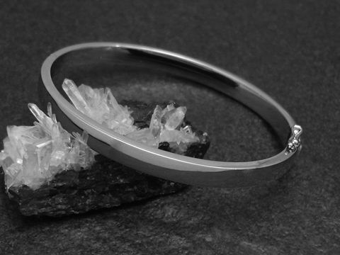 Silber Armreifen - blank - 5,8 mm - rhodiniert - 18 cm, Hersteller: Juwelier Harnisch, stilvoll abgebildet auf einem dunklen Untergrund mit Kristallen.