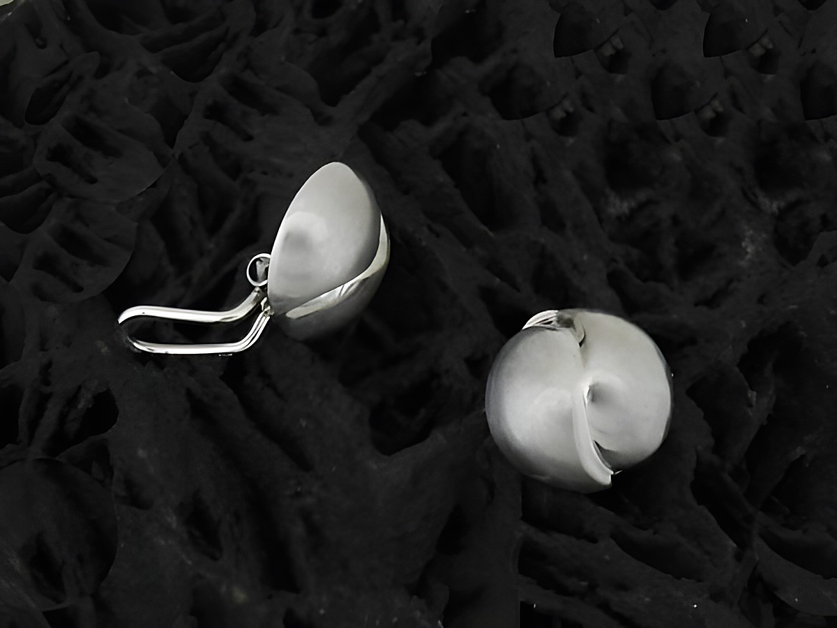 Design Ohrclips in schlichtem Stil aus sterling Silber rhodiniert, teilmattiert, vom Hersteller Juwelier Harnisch, präsentieren sich elegant und modern auf einer dunklen Unterlage.