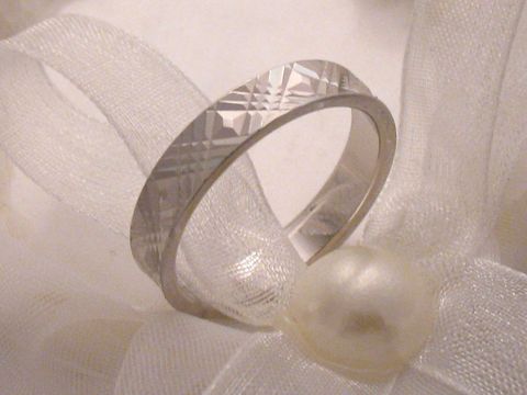 Trauring Ehering WHITE CROSS aus Weißgold 333, Größe 64/20,4, mit dekorativer Oberflächenstruktur, präsentiert auf einem zarten weißen Stoff mit einerPerle.