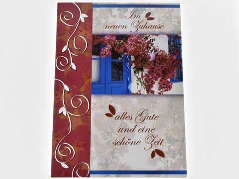 Blaue Tür mit Blumenstrauch und dekorativem Design, auf der Grußkarte steht der Text im neuen Zuhause alles Gute und eine schöne Zeit, Hersteller Juwelier Harnisch.