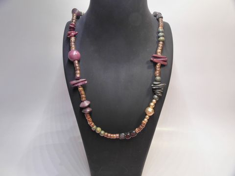 Bunte Holzkette mit verschiedenen Formen und Farben, 20 mm dick und 90 cm lang, hergestellt von Juwelier Harnisch, an einem Schmuckständer präsentiert.