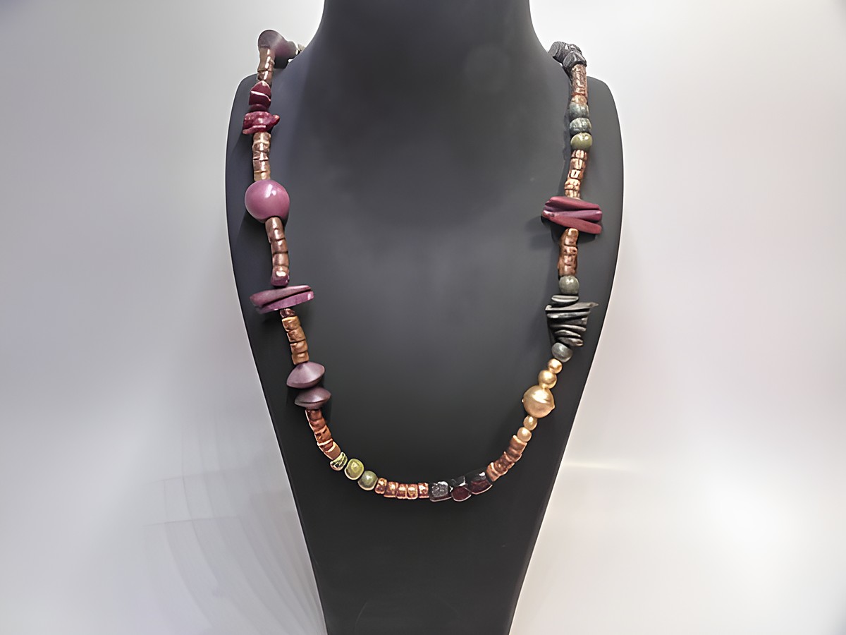 Bunte Holzkette mit verschiedenen Formen und Farben, 20 mm dick und 90 cm lang, hergestellt von Juwelier Harnisch, an einem Schmuckständer präsentiert.