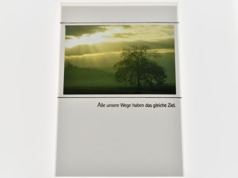 Trauerkarte mit einem stilisierten Baum im Vordergrund, umgeben von einer stimmungsvollen Landschaft und einer lichtdurchfluteten Himmelsszene, mit dem Text Alle unsere Wege haben das gleiche Ziel.