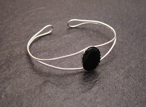 Facettierter Onyx Cabochon in ovaler Form auf schmalem Sterling Silber Armreifen, Umfang 18 cm, stilvolles Schmuckstück von Juwelier Harnisch.