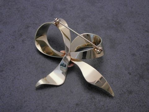 Gold Brosche symbolisch in Form einer Schleife, Anstecknadel, Gold 585, hergestellt von Juwelier Harnisch, attraktiv und elegant für besondere Anlässe.