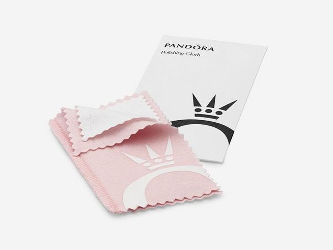 Pandora Schmuckputztuch in Rosa, Maße 12x6,5 cm, ausgelegt neben einer Anleitung. Ideal zur Pflege von Schmuck, angeboten von Juwelier Harnisch.