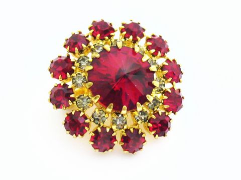 Rote Strass Brosche im Sexy City Look, rund, mit funkelnden roten und grauen Strasssteinen eingefasst in goldfarbenem Metall, Hersteller Juwelier Harnisch. Ideal für jeden eleganten Auftritt.