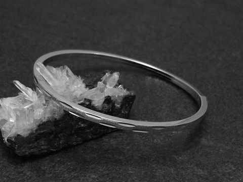Silber Armreifen modern 3 mm rhodiniert 18 cm von Juwelier Harnisch auf einem schwarzen Hintergrund mit Kristallen, elegant und zeitlos im Design.