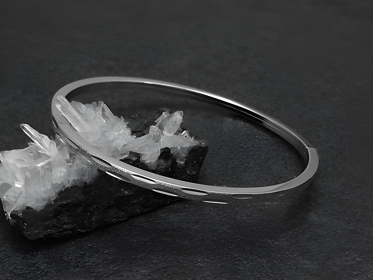 Silber Armreifen modern 3 mm rhodiniert 18 cm von Juwelier Harnisch auf einem schwarzen Hintergrund mit Kristallen, elegant und zeitlos im Design.