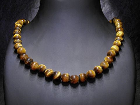Tigerauge Kette 8 mm goldbraun 47 cm von Juwelier Harnisch, Steinketten. Die Kette zeigt glänzende, runde Tigerauge Perlen in verschiedenen braunen Tönen, elegant auf einem schwarzen Hintergrund.