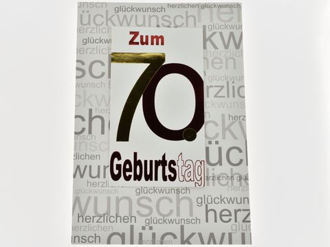 Geburtstagskarte zum 70. Geburtstag in rot und gold auf bedruckter Karte, Hersteller: Juwelier Harnisch, mit dem Aufdruck "Zum 70. Geburtstag" und verschiedenen Glückwunsch-Texten im Hintergrund.