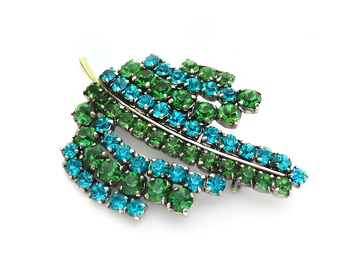 Brosche Sexy City Look Einzelstück in Grün Blau von Juwelier Harnisch, geschmückt mit Strasssteinen, die in verschiedenen Grüntönen und Blau funkeln, ideal für stylische Akzente.