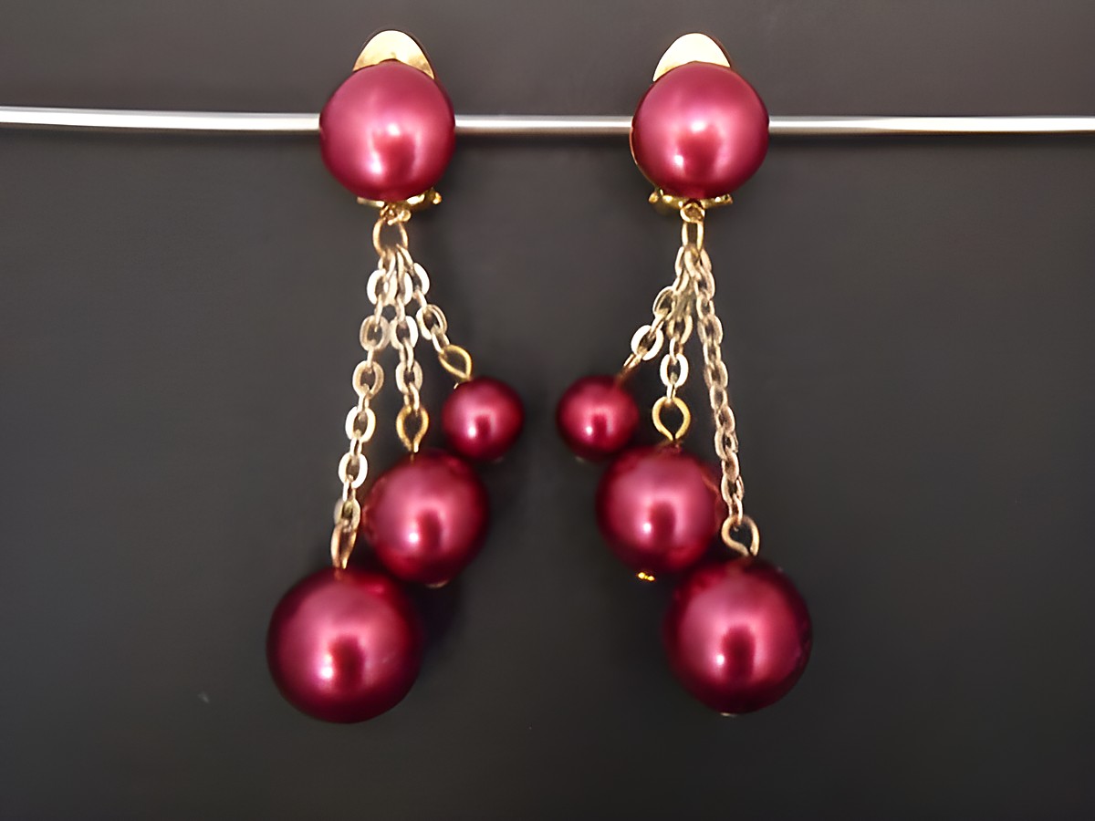 Himbeerrote Ohrclips aus Kunstharz mit goldfarbenen Akzenten, elegant und zeitlos gestaltet, bieten eine stilvolle Ergänzung für jedes Outfit, Hersteller Juwelier Harnisch.