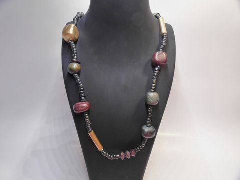 Holzkette Multiform 19 mm bunt 80 cm Holz Schmuck von Juwelier Harnisch, zeigt eine kreative Anordnung farbiger Holzelemente auf einem schwarzen Träger.