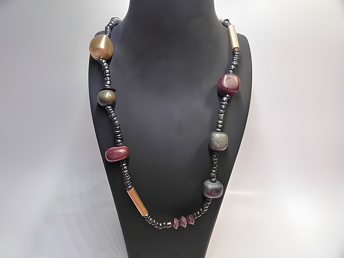 Holzkette Multiform 19 mm bunt 80 cm Holz Schmuck von Juwelier Harnisch, zeigt eine kreative Anordnung farbiger Holzelemente auf einem schwarzen Träger.