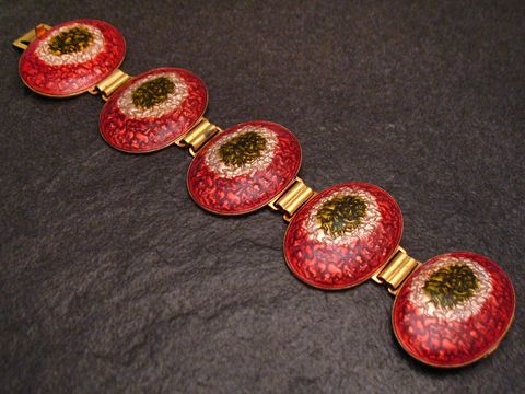 Ein modernes Armband in rot-weiß-oliv, 19 cm lang, mit emaillierten, ovalen Elementen und vergoldeten Verbindungen, hergestellt von Juwelier Harnisch, ideal für stilvolle Akzente.
