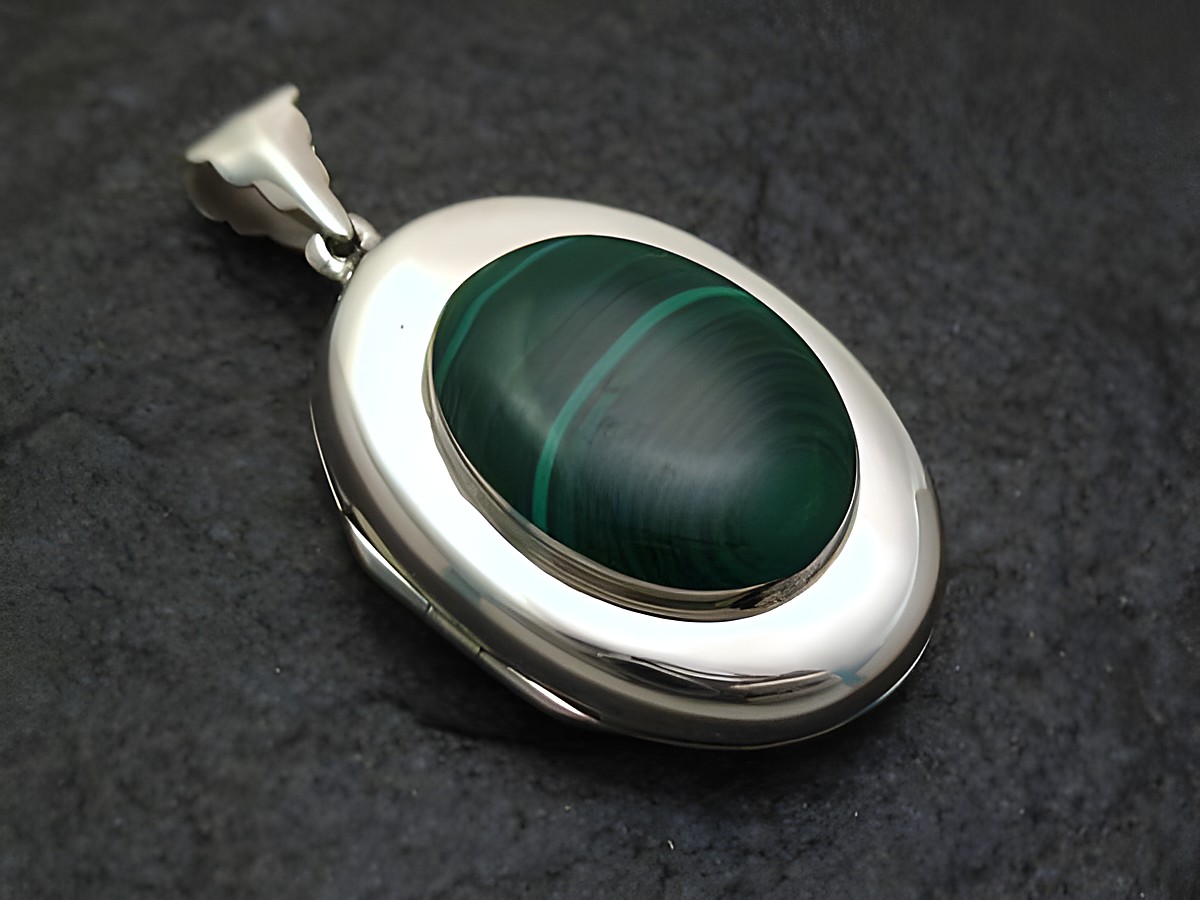 Ovales Malachit Medaillon aus 925 Sterling Silber, hergestellt von Juwelier Harnisch, mit schöner grün-brauner Musterung und glänzender Oberfläche. Ideal als elegantes Schmuckstück.