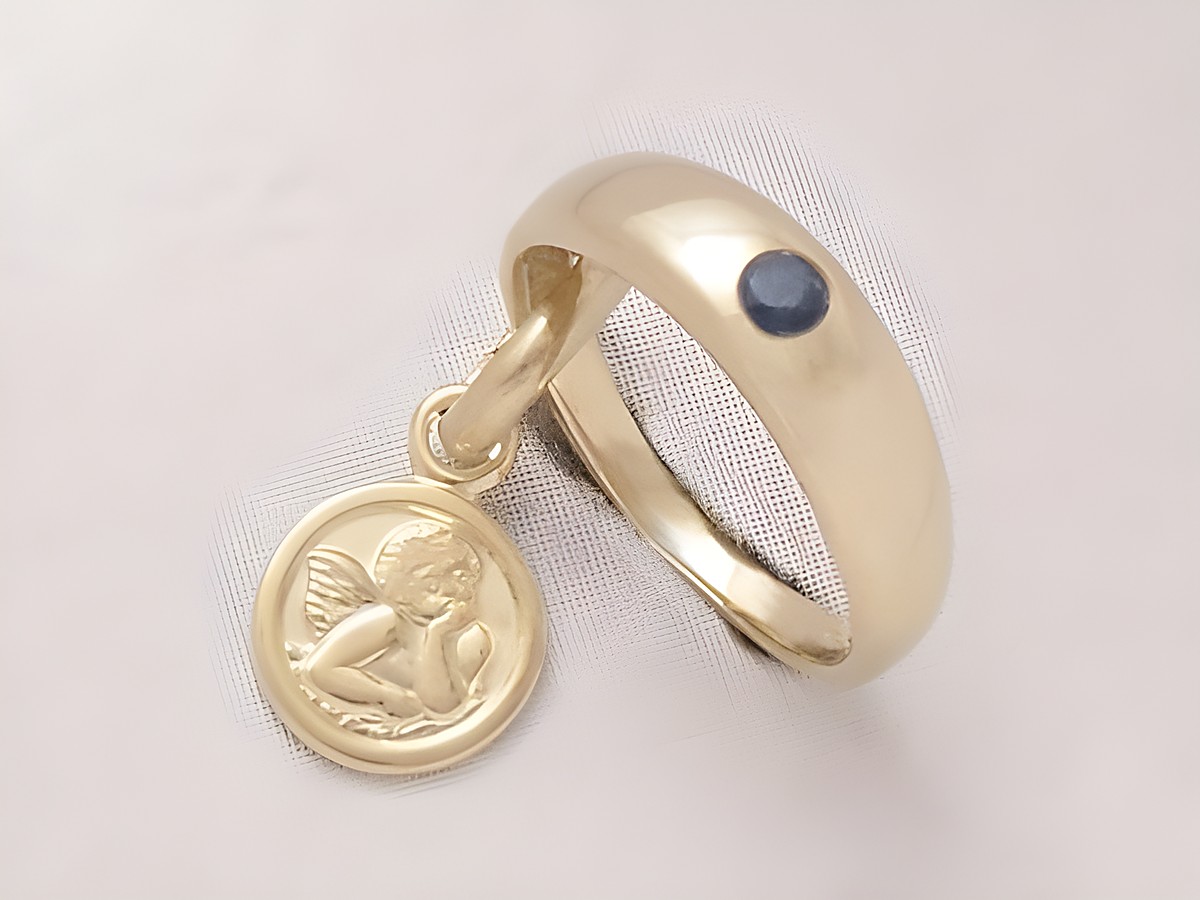 Taufring und Schutzengel in 925 Silber vergoldet mit Saphir, gefertigt vom Juwelier Harnisch. Der Ring hat einen Anhänger mit einem Engel und einem blauen Stein.