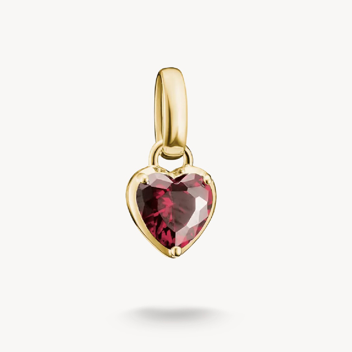 Charm in herzförmiger Form aus 18k Gelbgold mit einem roten Zirkonia Granat, ideal als Geburtsstein für Juli, von Thomas Sabo, neu und ansprechend gestaltet.