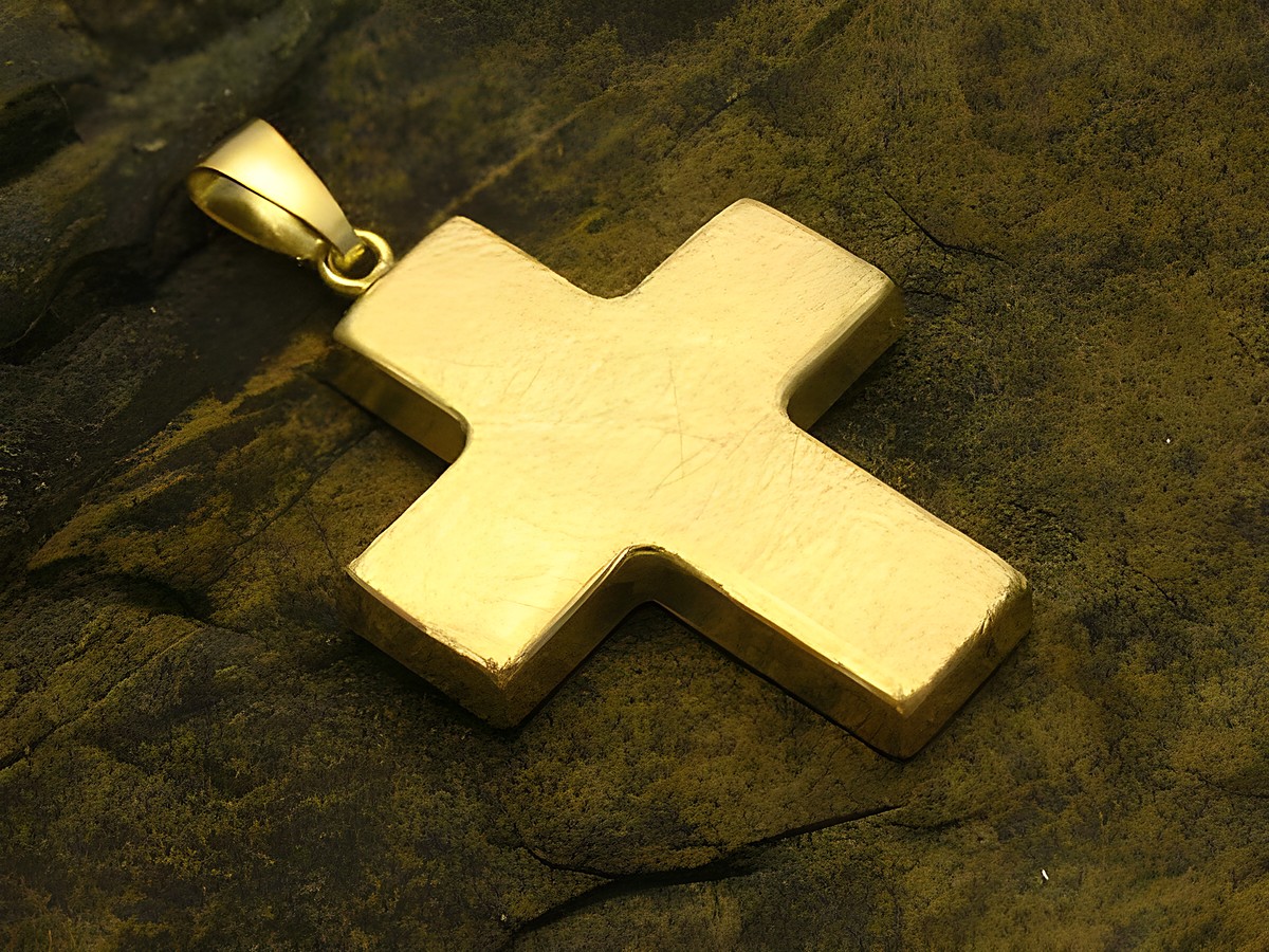 Kreuz aus Gold 333, Anhänger in klassischem Design, hergestellt von Juwelier Harnisch, auf rauem Untergrund platziert, mit glatter und glänzender Oberfläche.